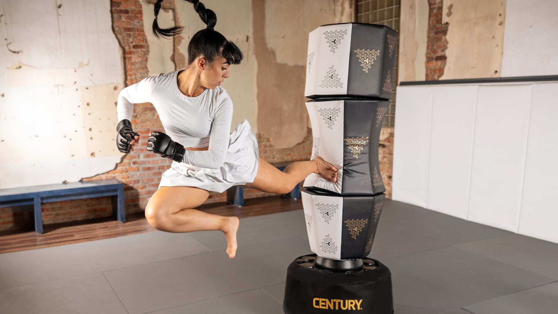 Martial artist mid-air delivering a powerful side kick to the Century Vario Wavemaster modular punching bag, showcasing versatility and full-body striking training in a modern martial arts studio.