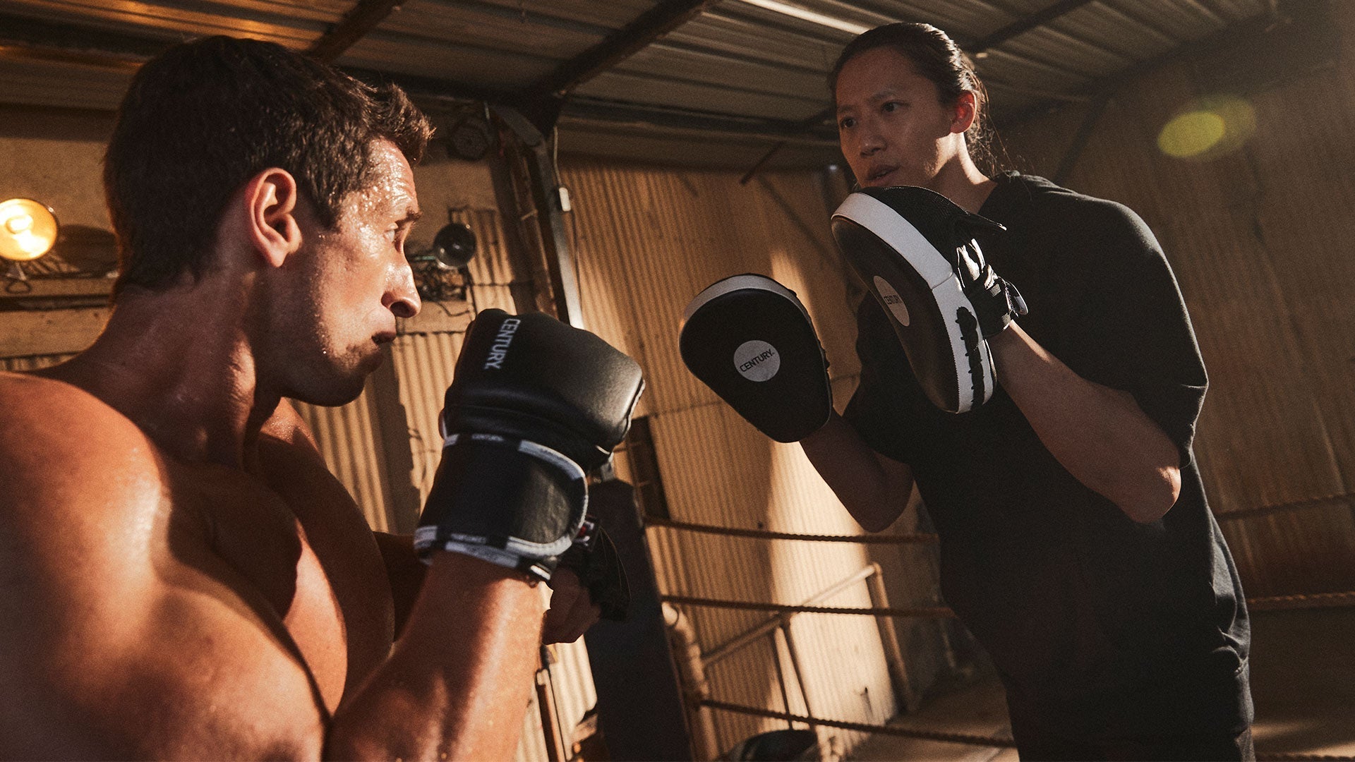 Coach holding Century focus mitts for a boxer