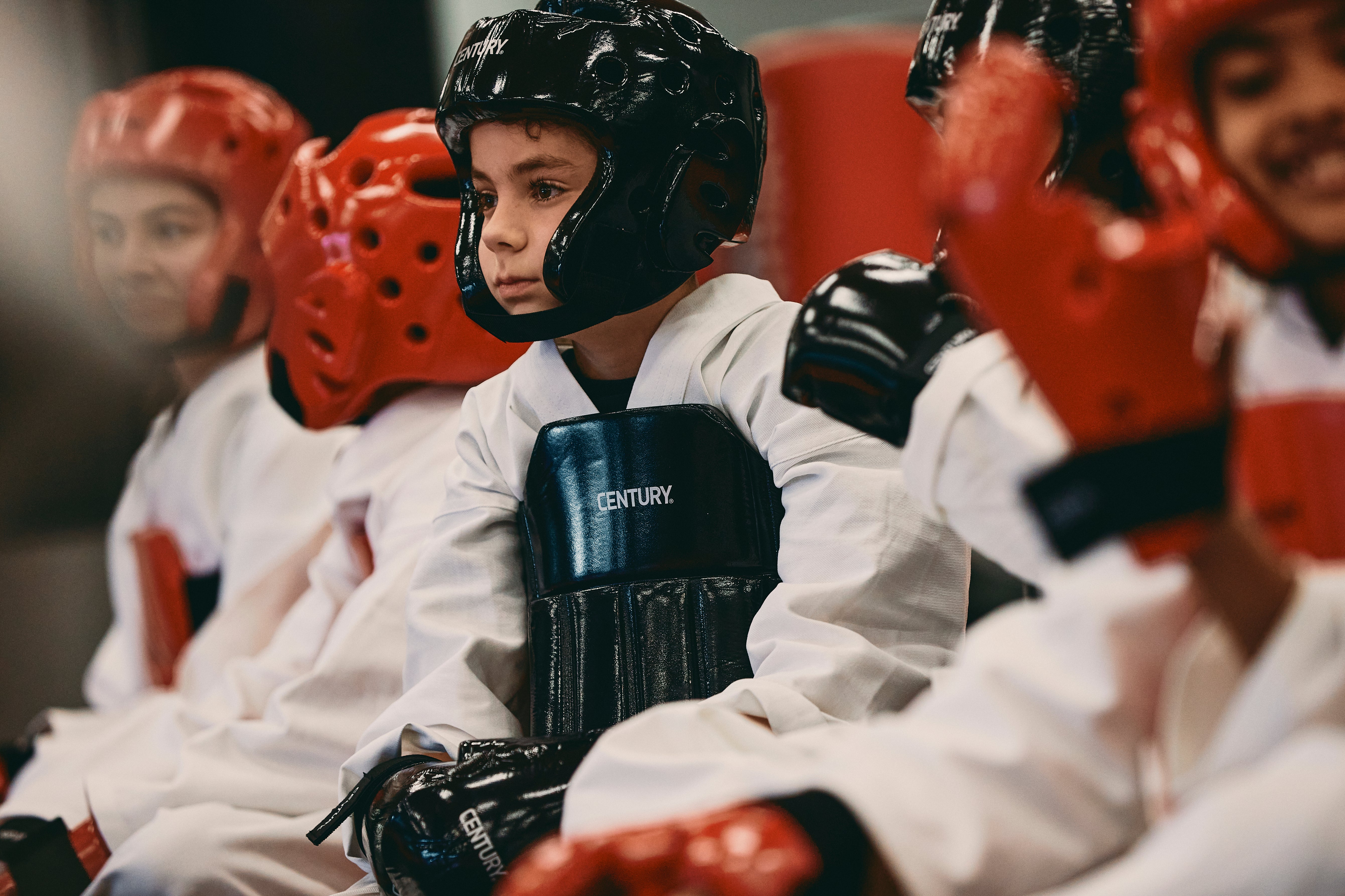 kids wearing sparring gear, sitting on the mat