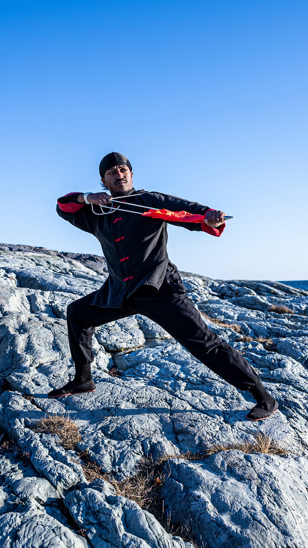 Rob Campbell posing in Kung Fu uniform on rocks near ocean